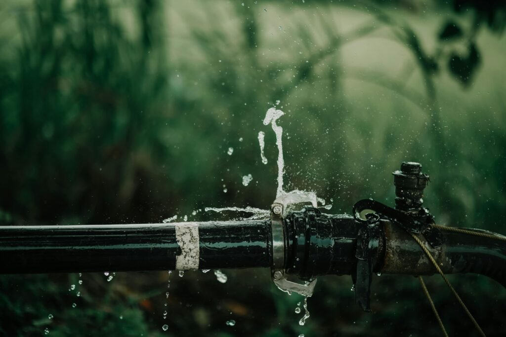 pexels-photo-18274115-18274115 A detailed view of a leaking water pipe in a lush green garden setting.